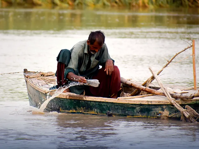An elderly fisherman in a wooden boat on the water in Sindh