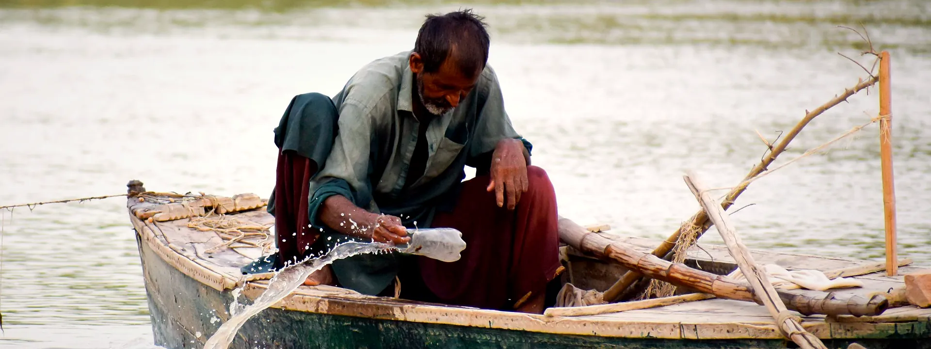 An elderly fisherman in a wooden boat on the water in Sindh