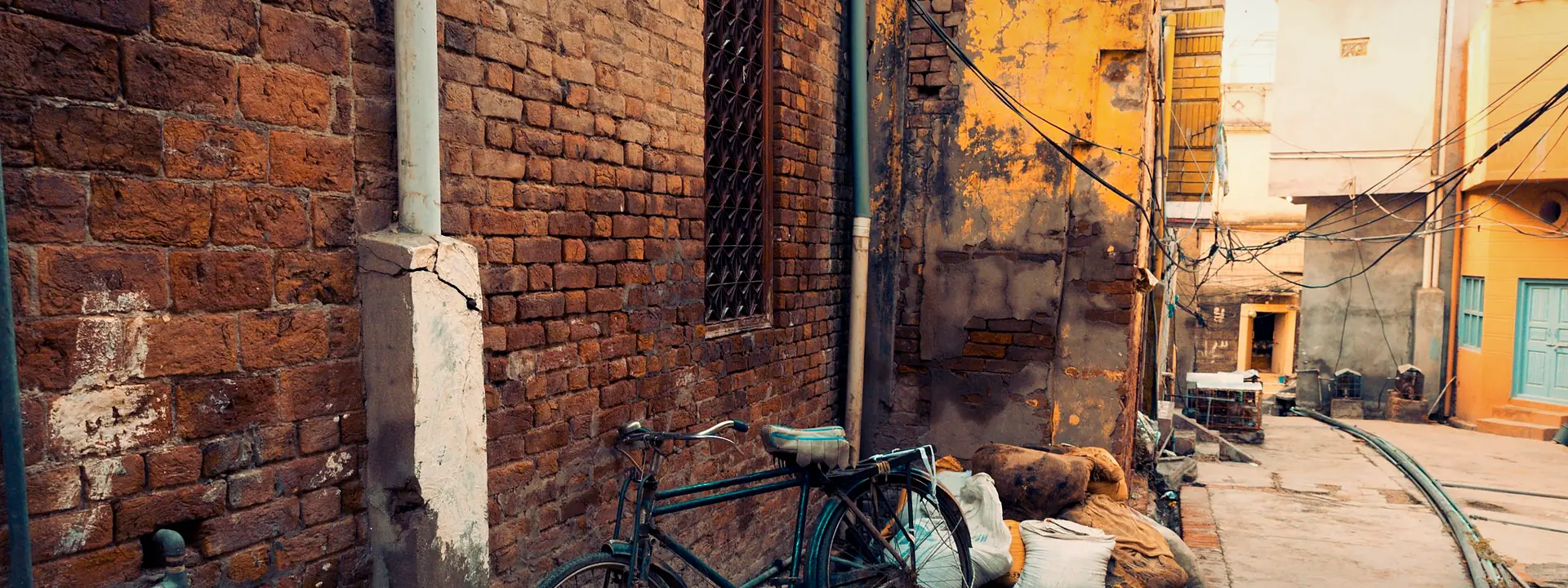 An old bicycle leaning on a weathered brick wall in a quiet Chiniot alley