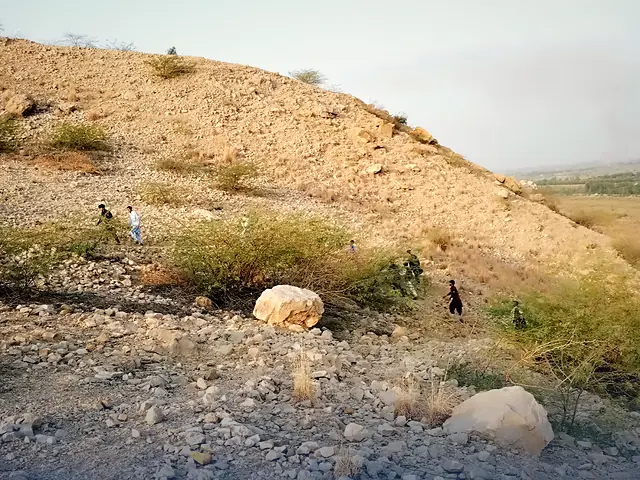 A group exploring the rocky landscape of Dera Ismail Khan under a clear blue sky