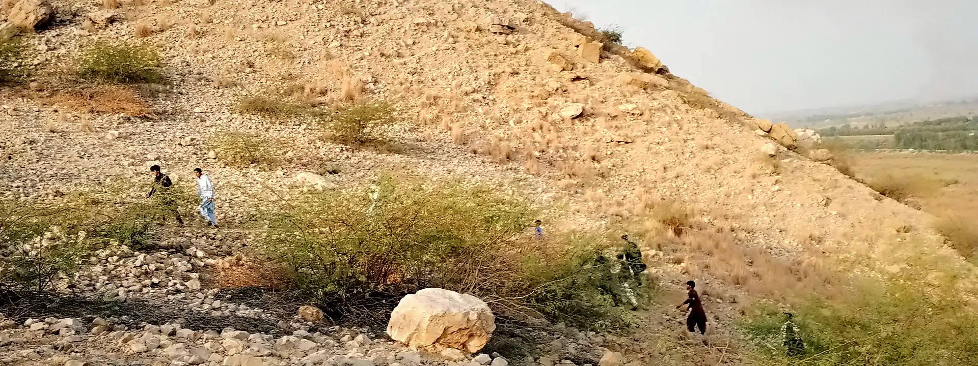 A group exploring the rocky landscape of Dera Ismail Khan under a clear blue sky
