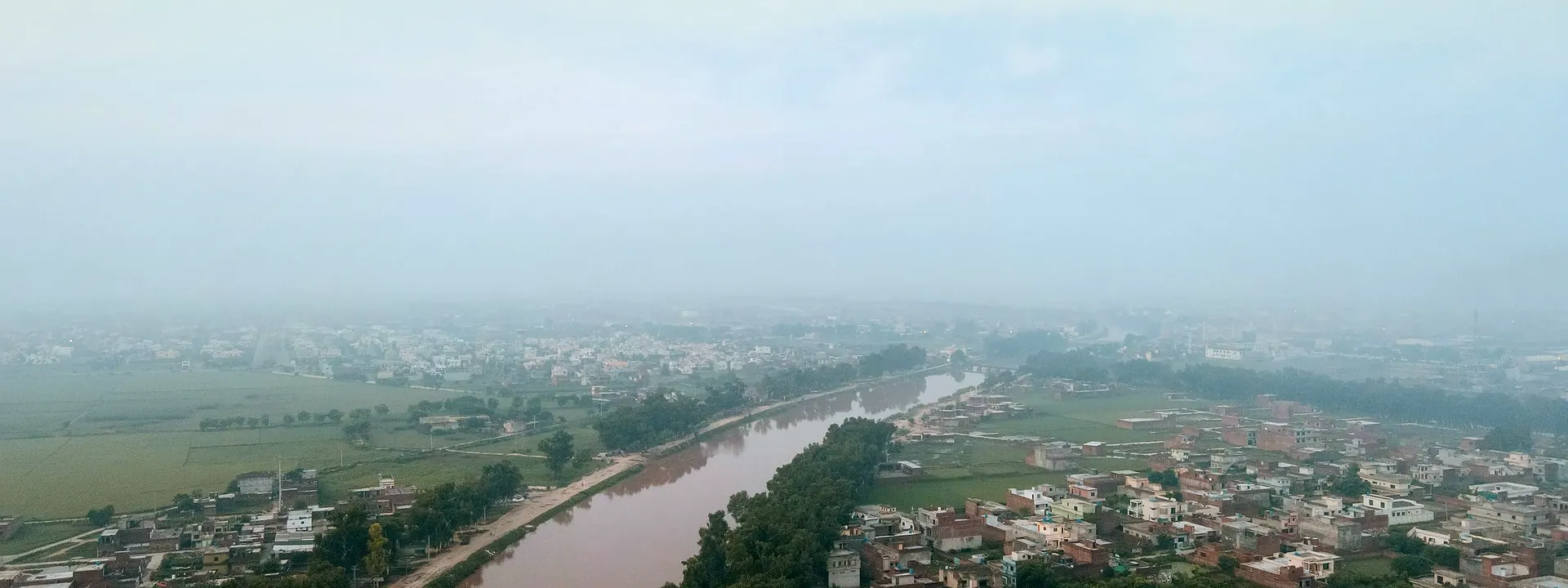 Aerial view of Gujranwala on a misty morning, with water channels running through the city