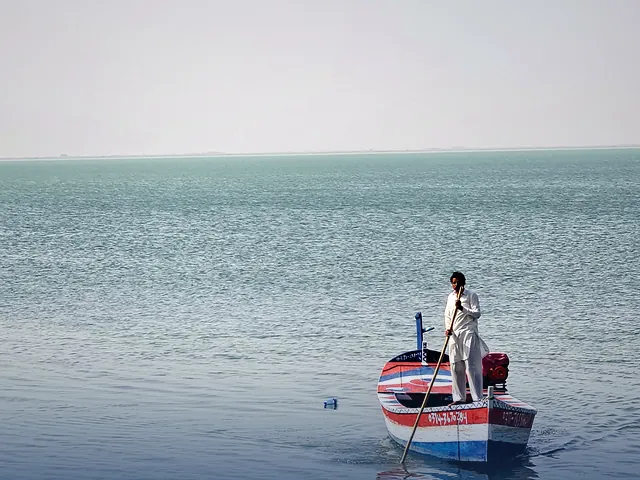 A fisherman paddling a boat on a calm lake in Mianwali