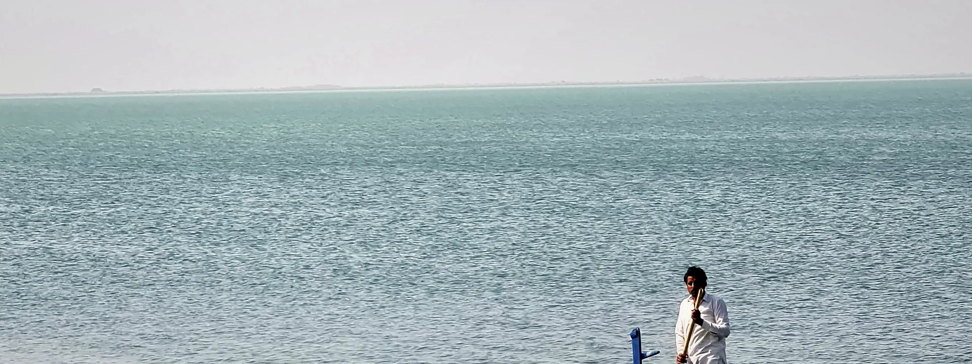 A fisherman paddling a boat on a calm lake in Mianwali