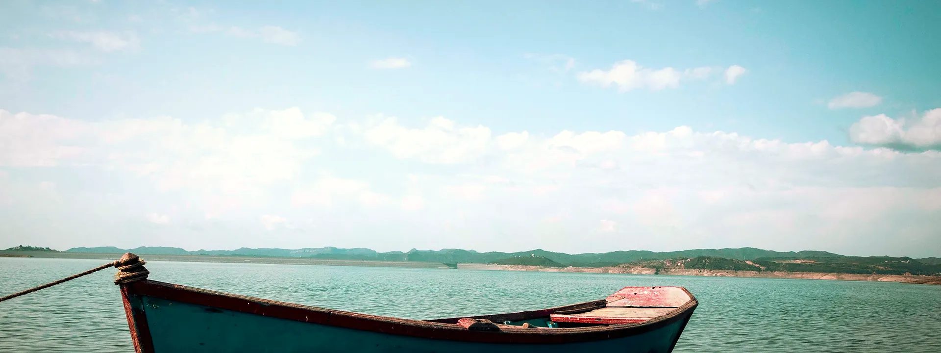 A wooden boat moored on the calm lake at New Mirpur City