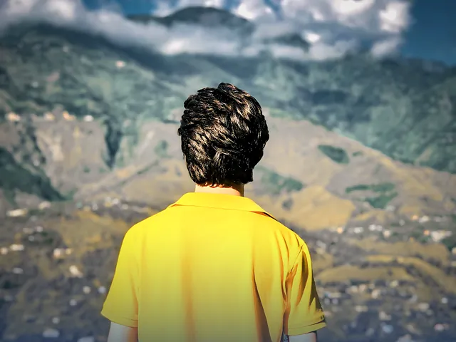 A man seen from behind looking out over the green mountains of Muzaffarabad