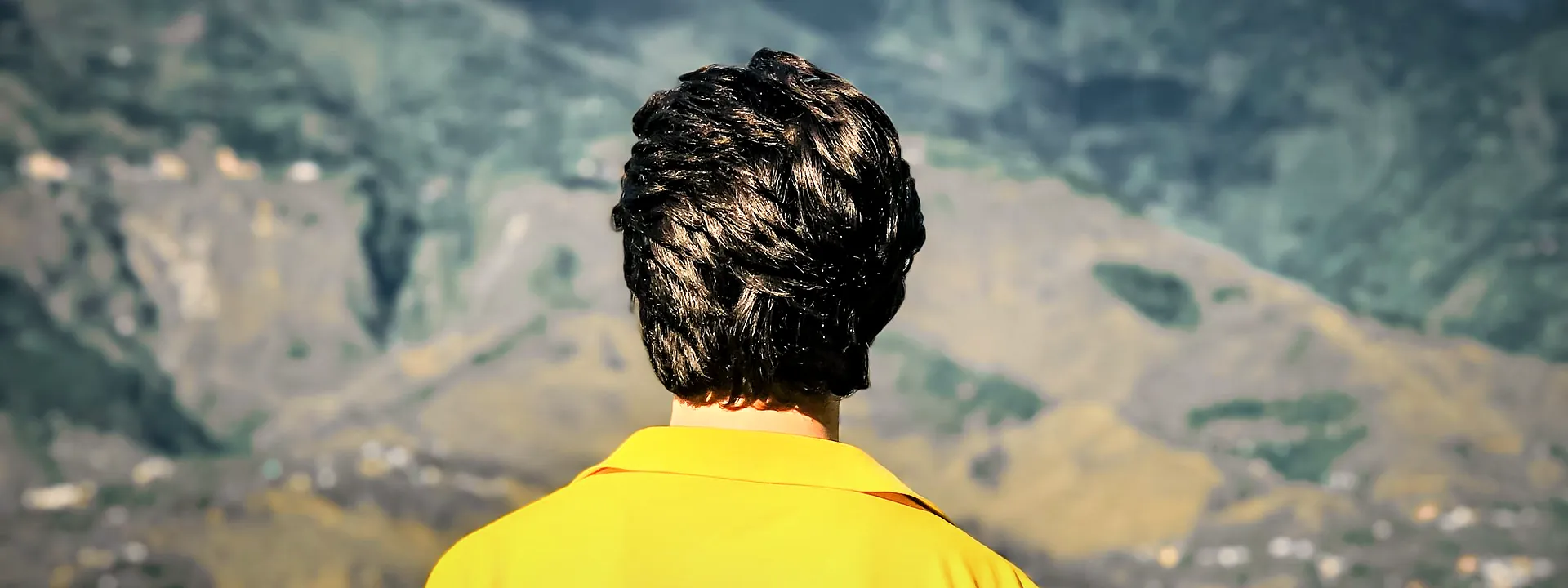 A man seen from behind looking out over the green mountains of Muzaffarabad
