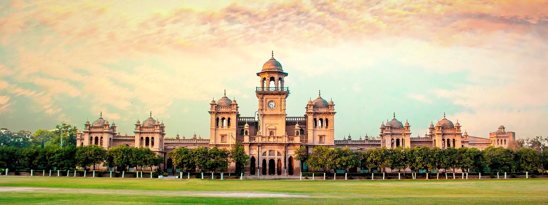 Islamia College Peshawar's domed facade against a vivid sunset sky