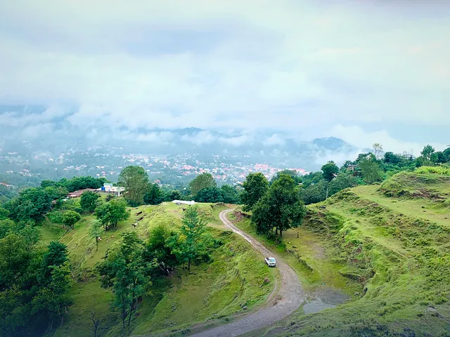 Aerial view of the green hills and a winding dirt road at Rawalakot