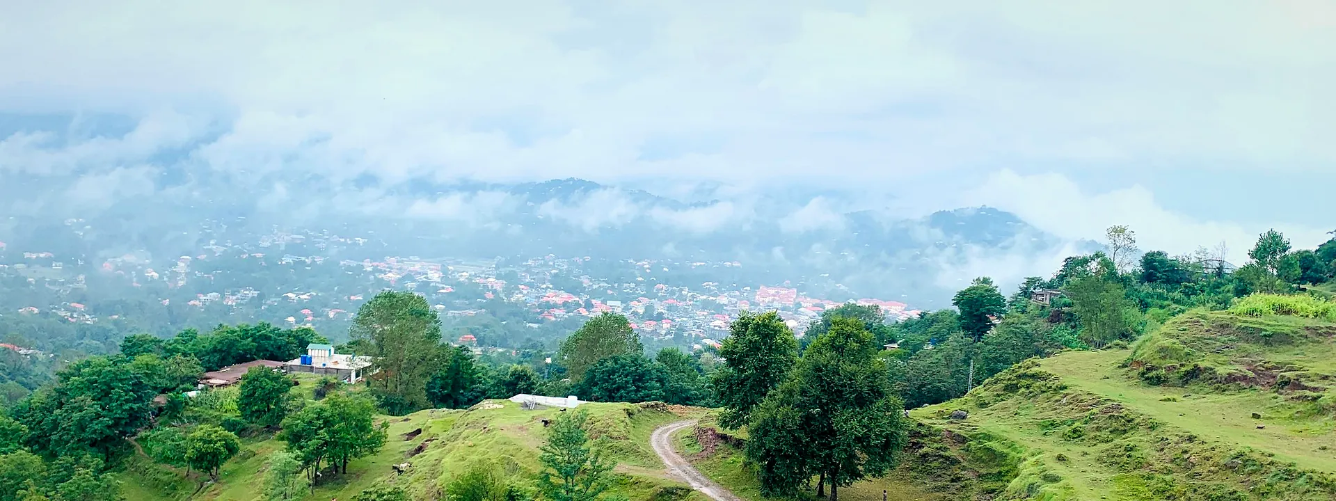 Aerial view of the green hills and a winding dirt road at Rawalakot