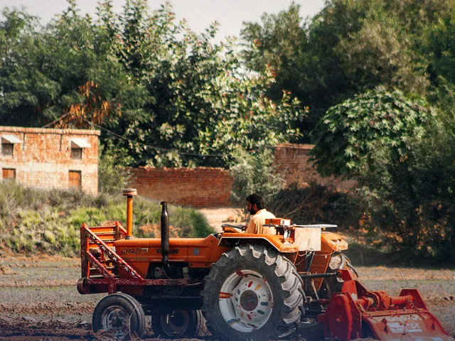 A farmer working a field with a tractor in Sadiqabad