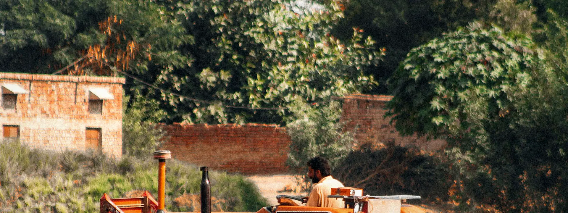 A farmer working a field with a tractor in Sadiqabad