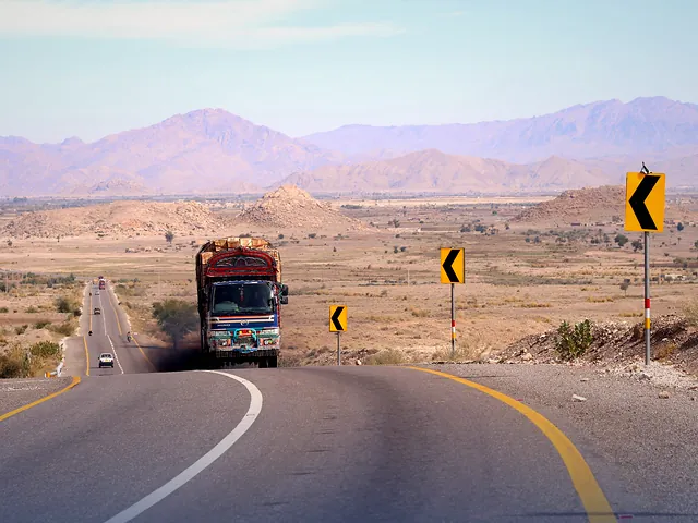 A colourful truck on a winding road through the arid mountains of Balochistan
